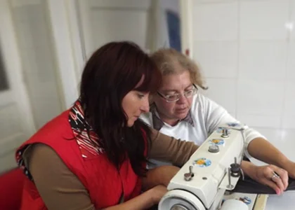 Beneficiară învățând să coasă la mașina de cusut, în cadrul programului de ocupație și formare
