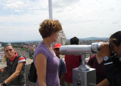 Beneficiari în timpul unei excursii, privind panorama orașului printr-un telescop turistic